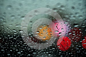 View of the night city through the window on a rainy night, raindrops fall on the windshield of the car. Concept life of