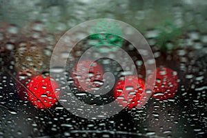 View of the night city through the window on a rainy night, raindrops fall on the windshield of the car. Concept life of