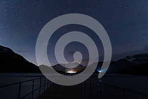 A view of the night sky from Aira Force steamer jetty with the glow of a car lights shinning through the trees