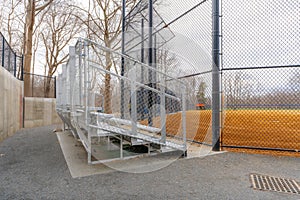 View of nondescript high school softball field aluminum bleachers located behind the backstop