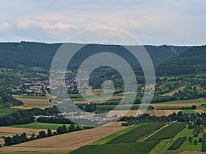 View of the northern foothills of Swabian Alb with forests, agricultural fields, rural village Hepsisau, Germany.