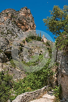 View of the Notre-Dame de Beauvoir church amidst cliffs and rock stairway.