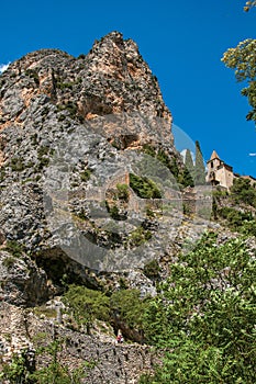 View of the Notre-Dame de Beauvoir church amidst cliffs and rock stairway.