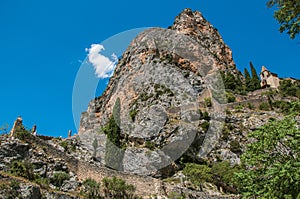 View of the Notre-Dame de Beauvoir church amidst cliffs and rock stairway.