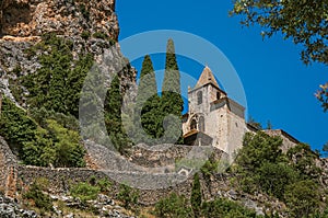 View of the Notre-Dame de Beauvoir church amidst cliffs and rock stairway.