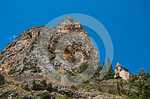 View of the Notre-Dame de Beauvoir church amidst cliffs and rock stairway.