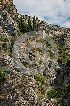 View of the Notre-Dame de Beauvoir church amidst cliffs and rock stairway, above the Moustiers-Sainte-Marie village.