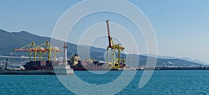 View of Novorossiysk commercial sea port in Tsemes bay. White lighthouse, yellow Port crane and Maersk containers