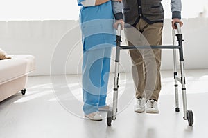 View of nurse walking with senior man in bright room