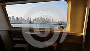 View of the ocean and the city with skyscrapers on the horizon from the cabin of a cruise liner.