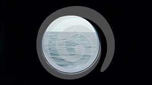 View of the ocean from the porthole of the ship going. A ship in the ocean is visible from the porthole of a cruise