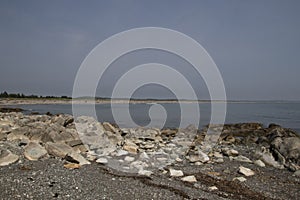 A view of the ocean seen over a foreground of rocks and gravel
