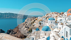 View of Oia town with traditional and famous houses and churches with blue domes over the Caldera on Santorini island. Greece