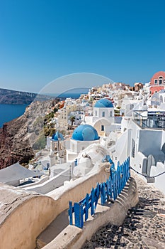 View of Oia town with traditional and famous houses and churches with blue domes over the Caldera on Santorini island.