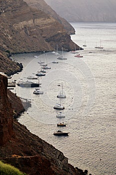 View from Oia village, Santorini island caldera, Greece. Boats in the harbor.