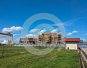 View of an oil rig construction site that is under construction with blue sky background.