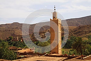 View on old berber arabian village with clay brick houses in valley with greenery and minaret