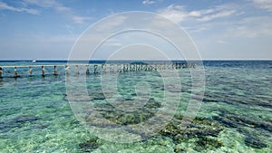 View of old broken jetty during sunny day with coral and green s