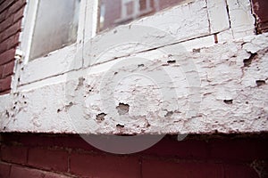 View of an old building window with flaky chipped paint on the wood and bricks