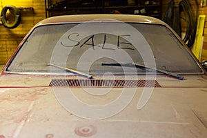 View of old car in garage with dusty hood dirty wind screen with title SALE by finger and broken windshield wip