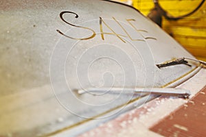 View of old car in garage with dusty hood dirty wind screen with title SALE by finger and broken windshield wip