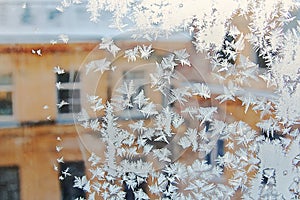 View of the old city house from a frozen winter window. Texture ice patterns on glass. Selective focus