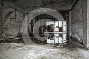 Old empty warehouse interior. Reflections in puddle