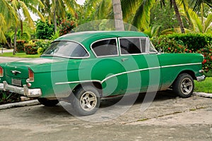 view of old green, customized retro vintage , classic car parked in tropical garden