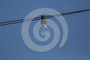 View of an old incandescent lamp, wired outside on the street with blue sky background