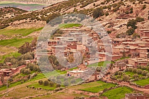 View of an old Kasbah in Morocco with adobe houses. mosque and green pastures