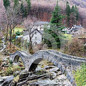 View of the old Roman stone bridge with two arches near the village of Lavertezzo in the Swiss Alps