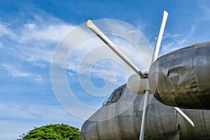 View of old and rusted airplane head parts and engine propellers parked in the parking lot against the background of forest and