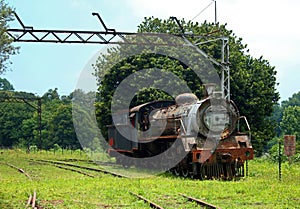 VIEW OF AN OLD RUSTED STEAM LOCOMOTIVE AT AN ABANDONED STATION