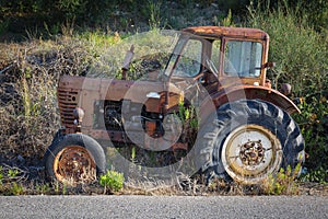 View of an old rusted tractor parked in nature.