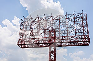 A view of an old sign, a red steel structure towering in anticipation of an advertisement