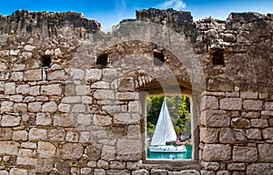 View through old stone window atsailing boat