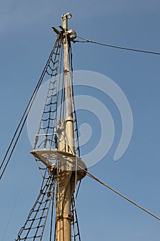 View of an old tall ship mast with rigging and shrouds against a deep blue sky