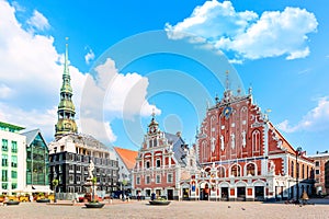 View of the Old Town Ratslaukums square, Roland Statue, The Blackheads House near St Peters Cathedral against blue sky in Riga,