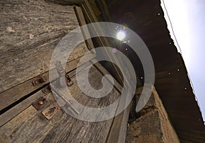 A view of an old wooden locked door of an abandoned house with sunburst in the background, India.