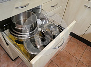 View of an open drawer with many stainless steel pots
