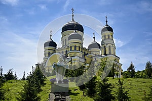 View of Orthodox Cathedral with domes in monastery against background of green landscape and cloudy sky. Hincu Monastery in