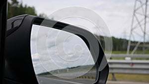 View out the rearview mirror as car drives on country road