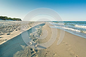 A view out to sea along the shoreline on a quiet beach on a bright sunny day