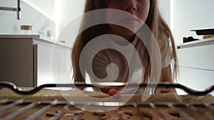 View from the oven: long haired teen girl opens the oven's door and puts a baking pan inside. Beautiful girl on kitchen