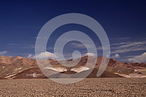 View over barren plain on brown hills contrasting with deep blue sky - Salar Salt flat near San Pedro de Atacama - Chile