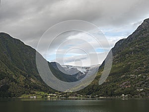 View over blue water of Hardanger Fjord in Kinsarvik on folgefonna glacier with small village on the coast. Norway