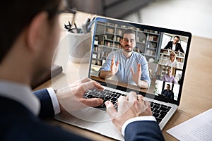 View over businessman shoulder laptop screen and videocall diverse participants