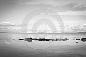 View over calm lake with rocks in the water in black and white