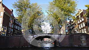 View over the canals of Amsterdam during water walking - bridges, boats, building facades, view from below