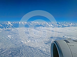 View over clouds from airplane with engine visible